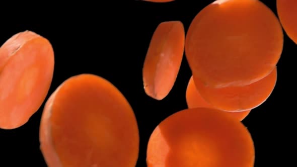 Super Closeup of Orange Juicy Carrot Slices Falling Diagonally in Slow Motion