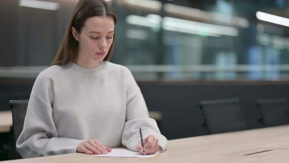 Beautiful Woman Writing on Paper in Office