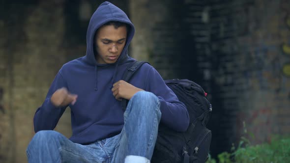 Sad Male Teenager With Face Wound Eating Sandwich Sitting Street, Family Problem