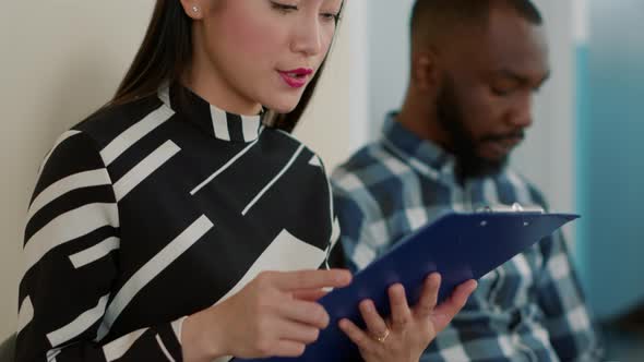 Female Candidate Looking at Recruitment Files in Queue at Job Interview