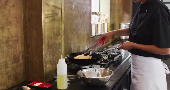 Mixed race female chef preparing a dish and smiling in a kitchen