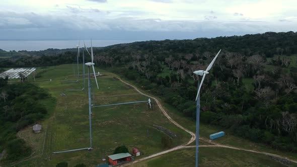 Aerial view of a wind farm situated on a mountain top near the coastline of a tropical island in the