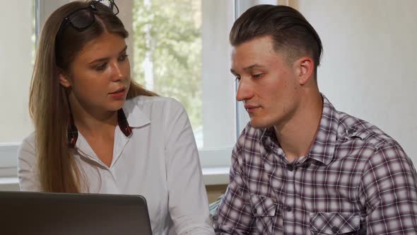 Two Business Colleagues Smiling To the Camera, While Using Laptop