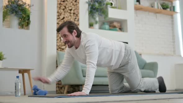 Young Man Doing Stretches on Yoga Mat at Home