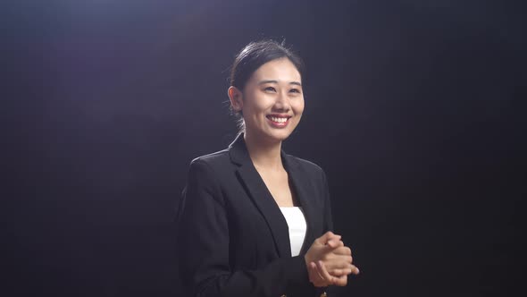 Smiling Asian Speaker Woman In Business Suit Clapping Her Hands And Looking Around On Stage