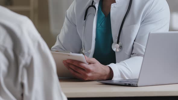 Closeup View Male Unknown Doctor Therapist Man in White Medical Uniform Sit at Desk Consult Patient