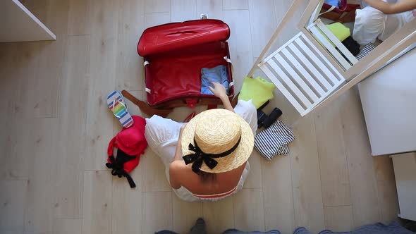 Young girl preparing for vacation. Pack up clothes in suitcase at home.