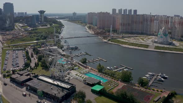 a Ferris Wheel on the River Bank with a Swimming Pool and a Beautiful Summer Landscape