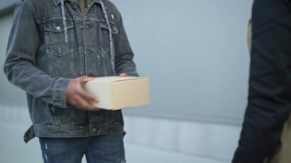 Male Courier Giving Parcel Box To Unrecognizable Female Client and Leaving