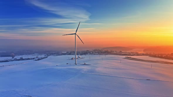 Wind turbine and snowy field in winter, aerial view