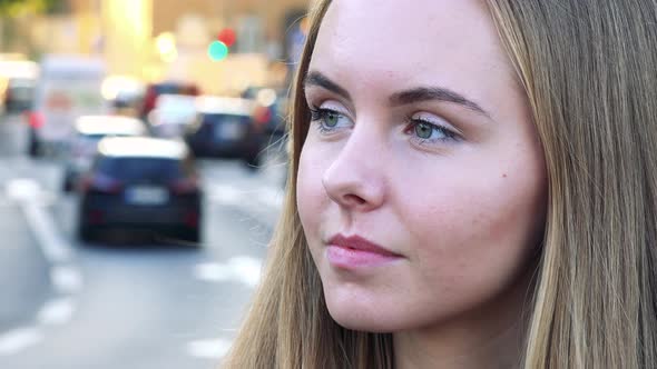 Young Beautiful Woman Looks Around in the City - Cars Passing in the Background - Closeup