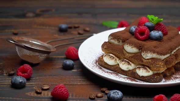 Portion of Classic Tiramisu Dessert with Raspberries and Blueberries on Wooden Background