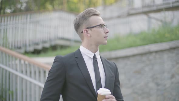 Portrait of Handsome Confident Young Businessman in Glasses Standing in Front of Stairs