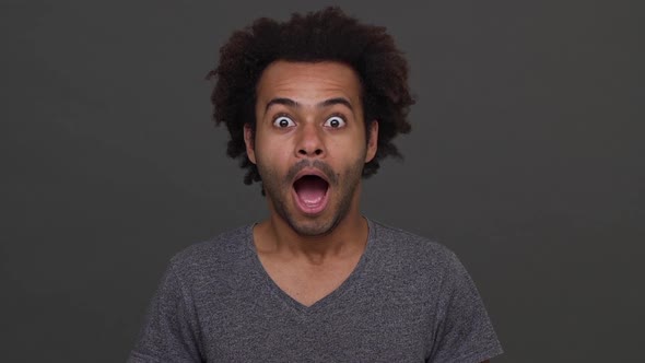 African American Young Male Joyfully Surprised Closing His Mouth with a Hand Isolated on Charcoal