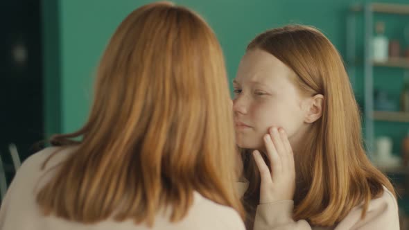 A Red Haired Teenage Girl Examines Her Reflection in the Mirror