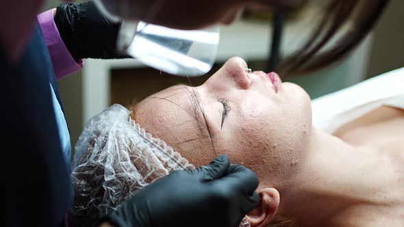Permanent Makeup Cosmetologist Master Takes Measurements for the New Shape of the Eyebrows of Model