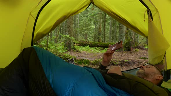 A Tourist Rests in a Tent in a Beautiful Forest