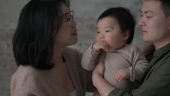 happy father holds his son in arms and together with mother, hugs  child tightly