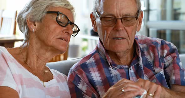 Senior couple discussing medication on sofa 4k