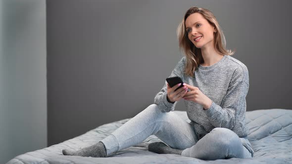 Pleasant Woman Smiling Chatting Surfing Internet Use Smartphone on Bed