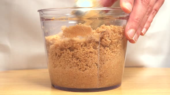 Stirring crushed biscuits to prepare cake base in bowl with metal spoon