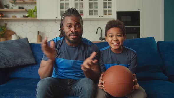 Happy African American Father and Son Watching Basketball Game on Tv at Home