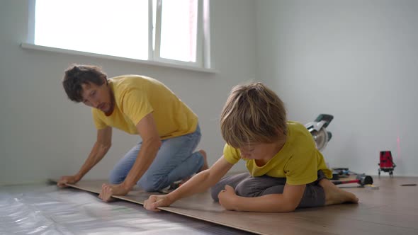 Father and His Little Son Install Laminate on the Floor in Their Apartment