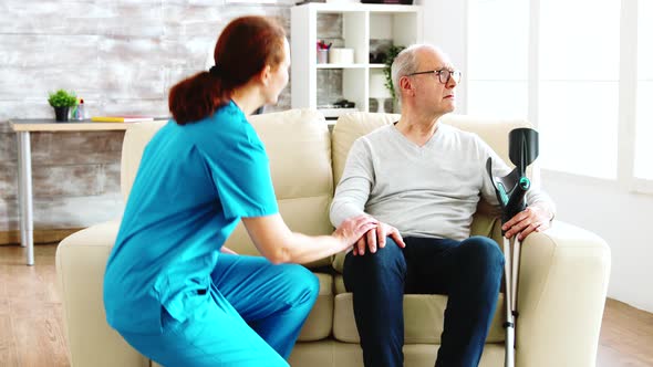 Female Nurse Looking After an Old Patient with Alzheimer Dissease Sitting on the Sofa in Nursing alt