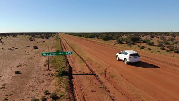 White SUV Car Traveling an Endless Straight Desert Road in the Australian Outback