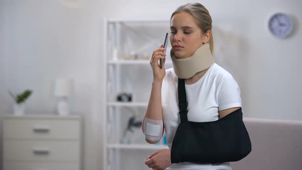 Displeased Woman in Foam Cervical Collar and Arm Sling Talking Phone, Bad News