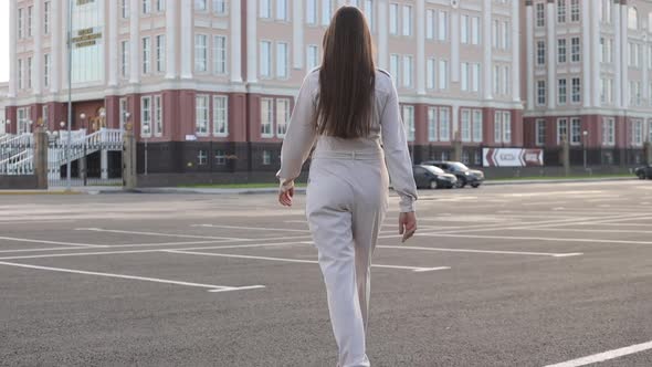 Back View of Funny Smiling Woman in Casual Clothes and Sunglasses Running on the Street Background