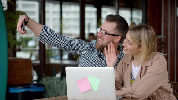 Young Cheerful Lady and Guy Are Photographing in Cafe By Mobile Phone