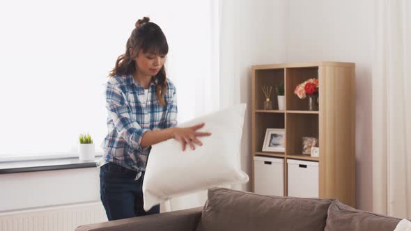 Asian Woman Arranging Sofa Cushions at Home