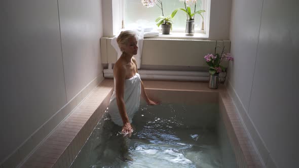 Steadicam shot of beautiful mature woman wearing towel in historic Roman Bath in Berkeley Springs St