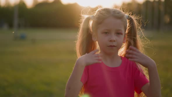 Tired Little Girl Waves to Cool Down in Park at Sunset