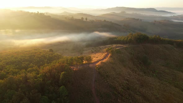 Aerial view of sunrise with fog above mountains. Golden hour and amazing sun rays. Nan, Thailand