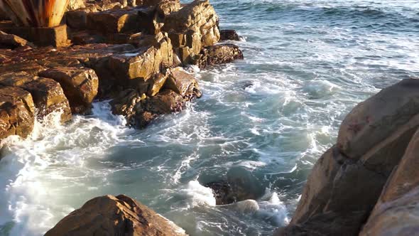 Waves crashing on rocks on sunny day at Plettenberg bay , South Africa.