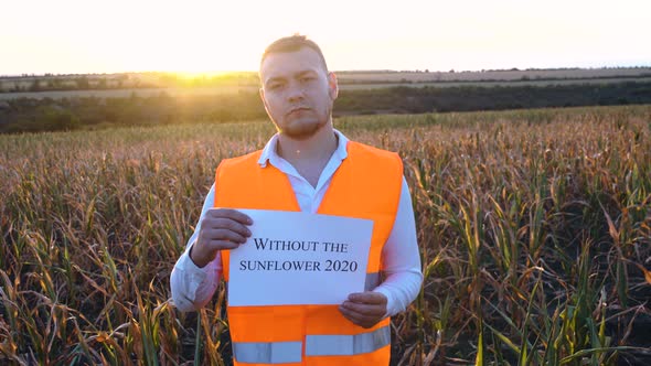 Portrait of a Sad Young Farmer Holding a Plaque with the Inscription No Sunflower in 2020.