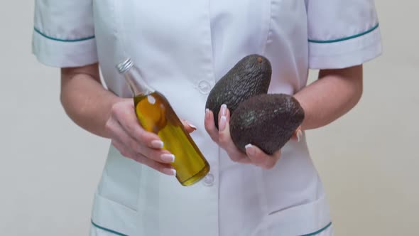 Nutritionist Doctor Holding Organic Avocado Fruit and Bottle of Oil