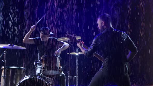 Emotional Performance of a Rock Band in a Dark Studio Illuminated By Blue Light in the Pouring Rain