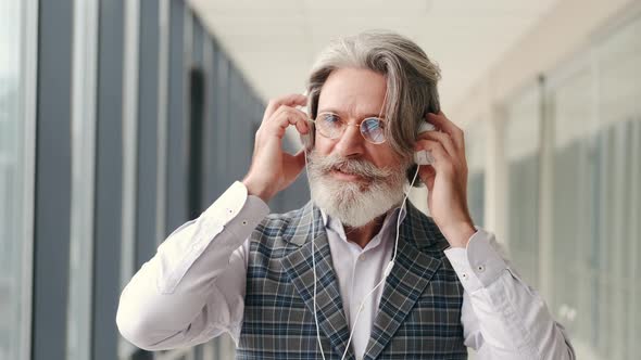 Hipster Businessman in Earphones Listening To Music with Smartphone