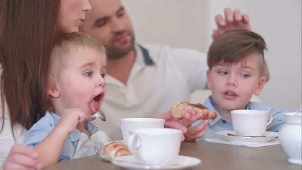 Two Little Boy Kids Having Tea with Pastry Together with Their Parents