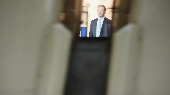 Man in suit waits on platform as train passes by, commuter going to work