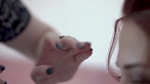 Stylist is Working on the Bride's Hair in the Morning Before the Wedding Sprinkles on Her with