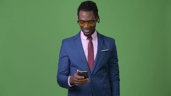 Young Handsome African Businessman with Dreadlocks Against Green Background