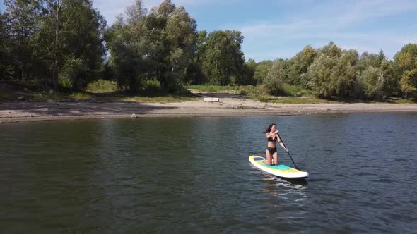 Caucasian Woman Riding a SUP Board on the Lake