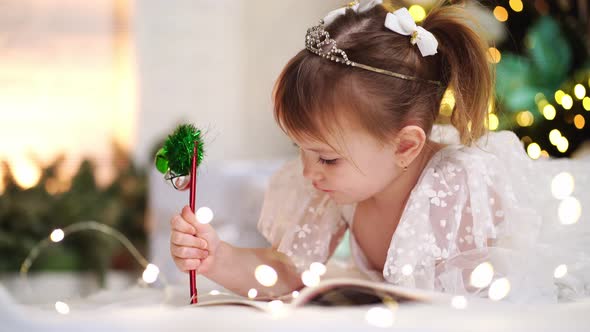 Little Girl Writes a Letter to Santa Claus Under the Christmas Tree