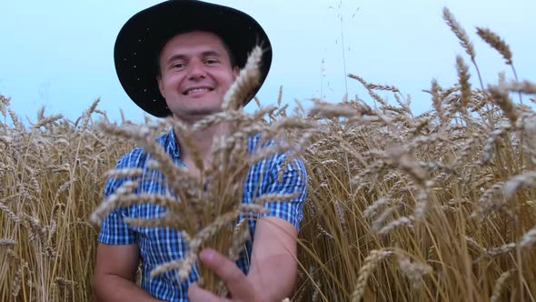 A young farmer, holding spikelets in his hands, rejoices in a good harvest.