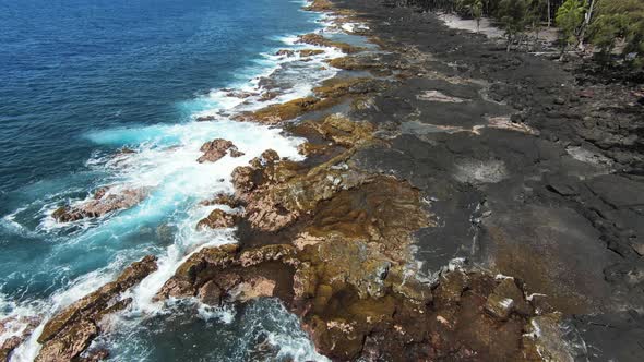 FPV slomo drone shot over blue ocean crashing on basalt shoreline