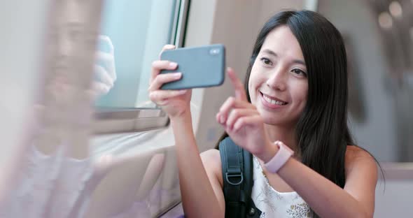 Woman taking photo with cellphone on Taipei city metro 